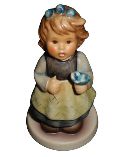 Goebel Hummel From The Heart 761 Girl in White Dress and Yellow Apron Holding Blue Flower Figurine Helmut Fischer